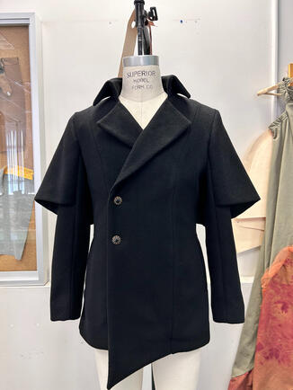 Crafted with 100% wool from Italy. Features asymmetric panels and a winged cloak inset to sleeves and back contour lines. A great combination for those who like cloaks and crave the warmth of a winter coat.